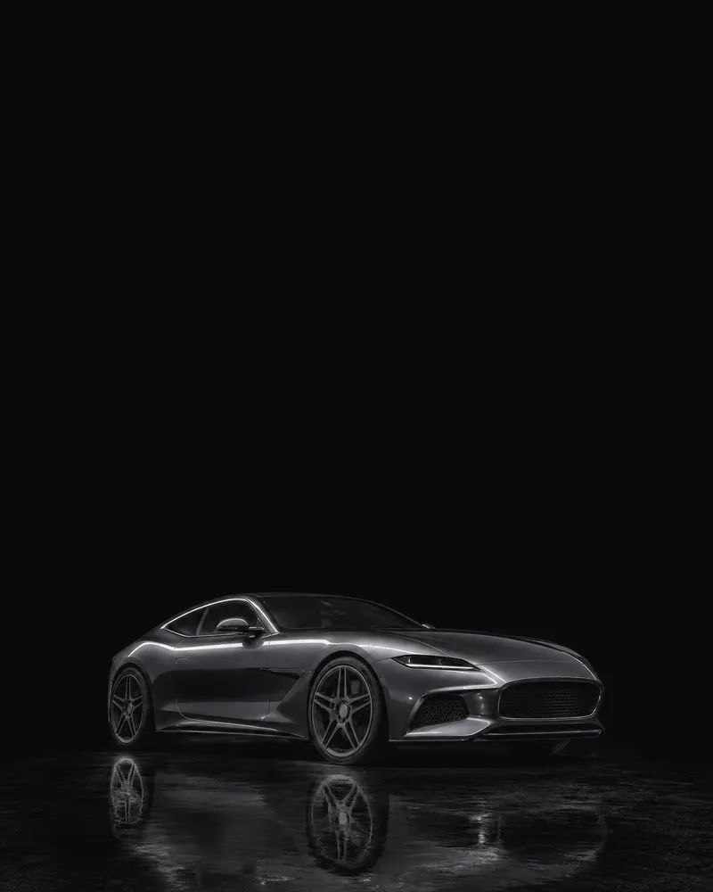 A graphite grand tourer on a black studio floor, lit by one strip light along its shoulder.